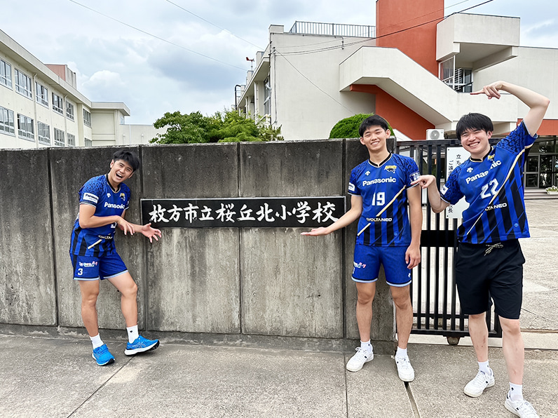 写真:校門前に立つ中村選手、西川選手、小宮選手