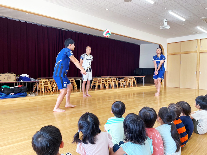 写真:選手が子供たちにパスを見せている様子
