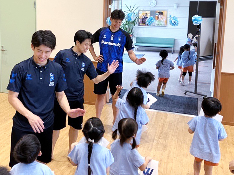写真：ハイタッチをする選手と子供たち