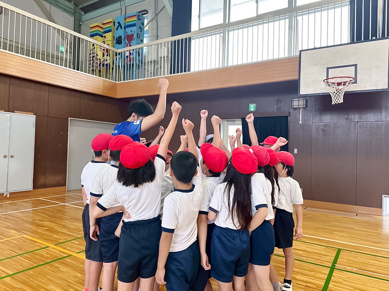 写真：円陣を組んで拳を上げる中村選手と子供たち