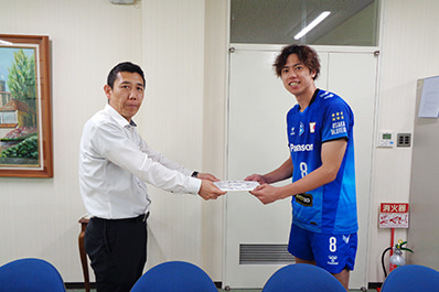 写真：選手のサイン色紙を贈呈する仲本選手（右）